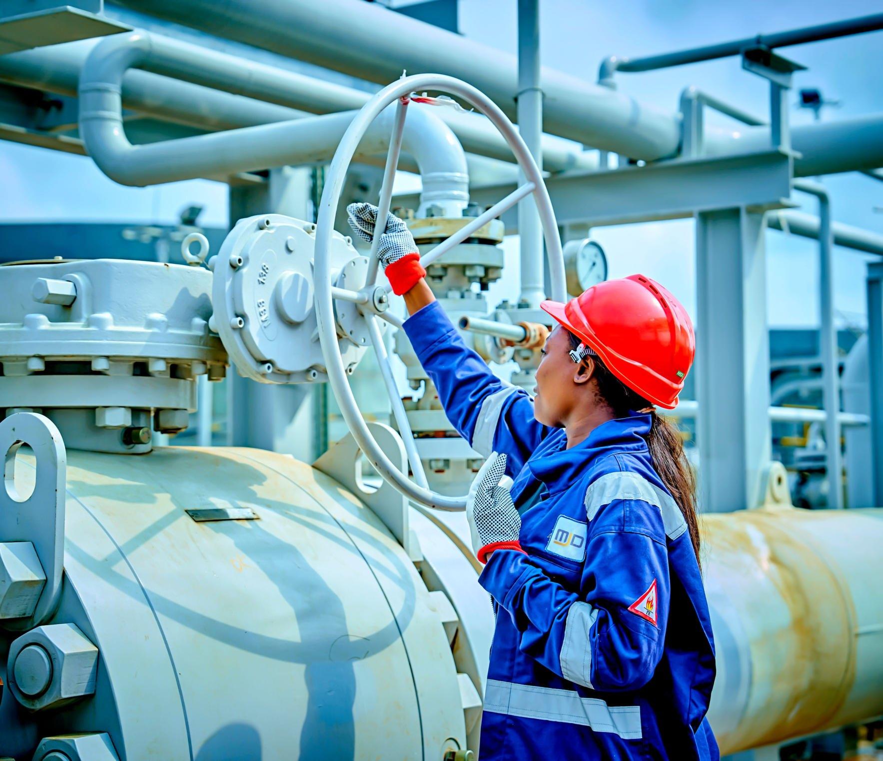 An MJD engineer operating a valve handwheel on a wellhead manifold